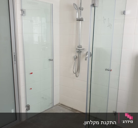 מקלחת עם דלתות זכוכית וראש מקלחת מתכתי